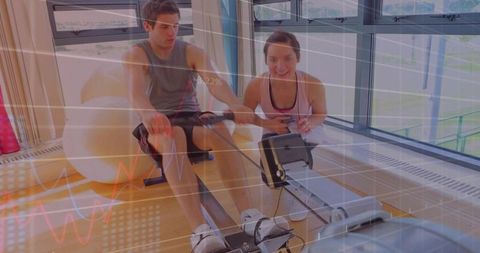 Couple Training on Rowing Machine While Trainer Monitors Performance in Bright Gym