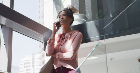 Confident Businesswoman Communicating Via Smartphone in Office Atrium