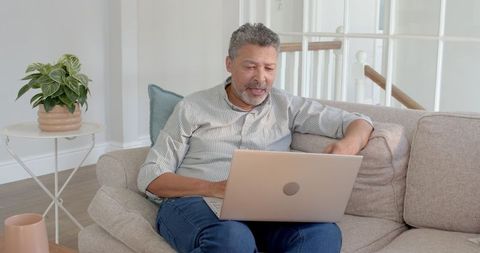 Senior Man Focuses on Laptop for Remote Work at Home