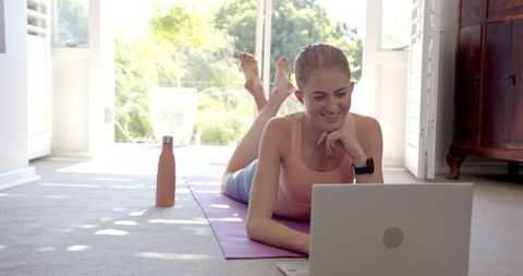 Young woman exercising at home with laptop yoga routine