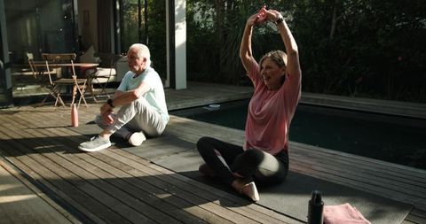 Senior Couple Enjoying Yoga on Deck near Pool