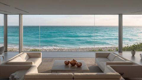 Minimalist beachfront living room overlooking turquoise sea through floor-to-ceiling glass