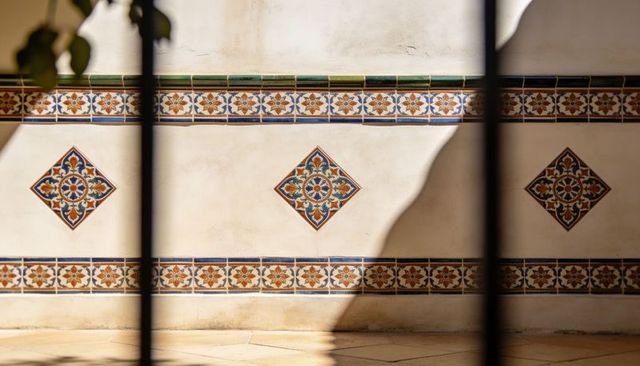 Sunlit mediterranean courtyard wall with ceramic medallions and patterned frieze