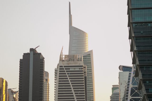 This image captures the modern skyline of Dubai with several iconic skyscrapers under the evening light. The blend of architectural styles showcases the city's futuristic development. Useful for articles on urban development, business districts, modern architecture, and Middle Eastern cities.