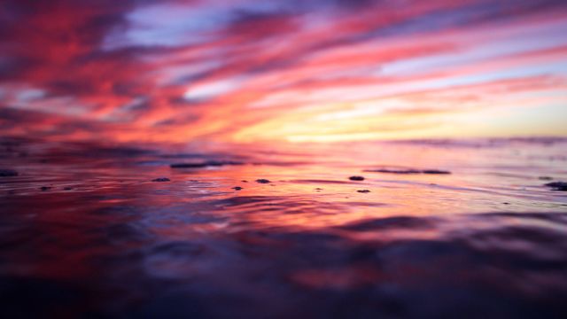Capture of a vibrant sunset reflecting over calm ocean waves. Ideal for backgrounds, travel and tourism promotions, nature and environmental topics, and wellness or relaxation themes.