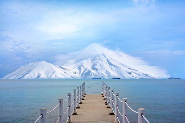 Scenic snowy mountain view from wooden pier over calm water - Download Free Stock Photos Pikwizard.com