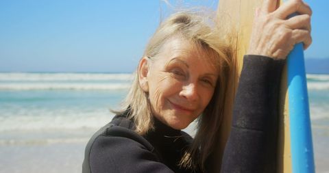 Smiling Senior Woman with Surfboard on Sunny Beach