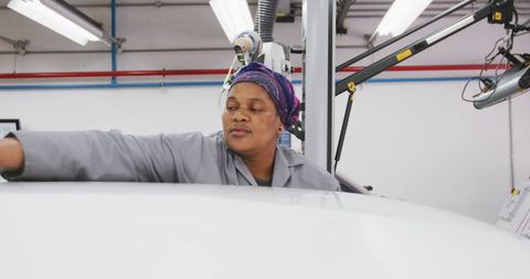 African american female mechanic detailing car in workshop