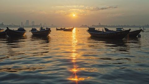 Tranquil sunrise with boats along serene bay of bengal coastline and city skyline