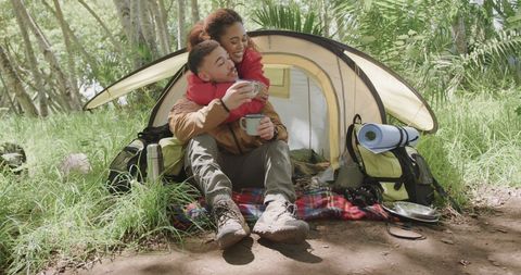 Happy Couple Enjoying Coffee While Camping in Forest