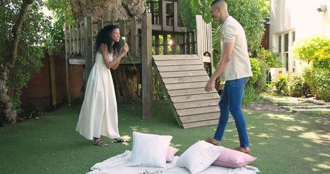 Joyful couple enjoying playful picnic in sunny backyard