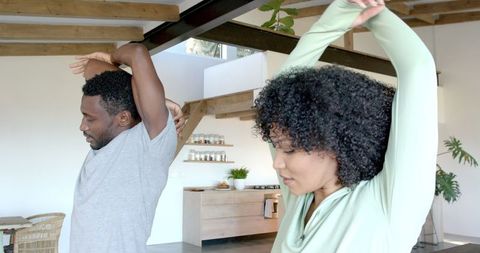 Couple Stretching Together in Modern Kitchen for Morning Exercise