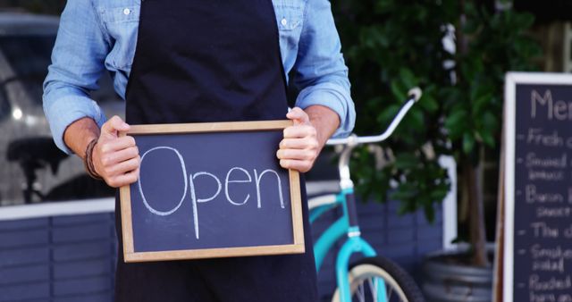 Waiter showing chalkboard with open sign outside the cafe 4k