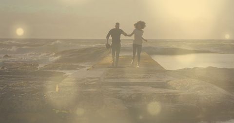 Romantic couple running hand in hand at beach