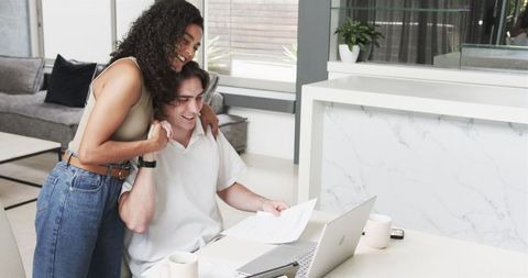 Happy Couple Reviewing Documents on Laptop at Home