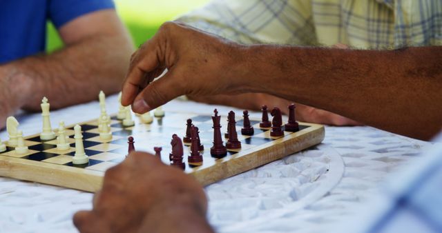 Seniors engaging in a game of chess while enjoying a sunny day outdoors. This photo can be used for content related to retirement lifestyle, mental exercise, social activities for older adults, or promotional material for senior community centers.
