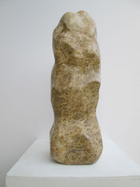 Abstract stone sculpture displayed on a white pedestal. The rough texture and natural colors add depth and interest to the contemporary artwork. Ideal for use in projects related to modern art, galleries, exhibitions, design showcases, and artistic craftsmanship promotions.