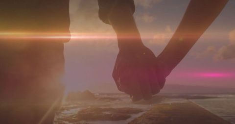 Romantic Sunset Silhouette: Couple Holding Hands by Ocean