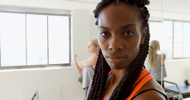 Confident Woman in Fitness Studio with Gym Members in Background - Download Free Stock Images Pikwizard.com