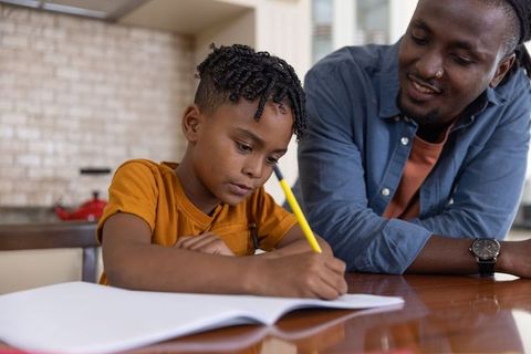 African american father mentoring son doing homework at kitchen table