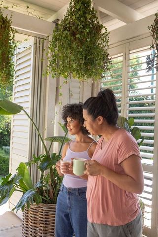 Mother and daughter relaxing on sunny porch surrounded by greenery