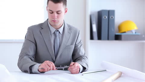 Architect in Office Setting Adjusting Compass for Design Work