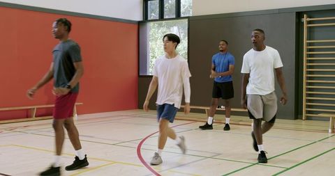 Diverse athletes walking on indoor court during basketball drill with african american player