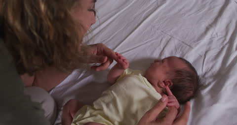 Warm Interaction Between Mother and Newborn Baby on Bed