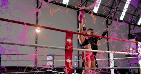 Trainer raising female boxer gloved hand after victory in ring with pink gloves