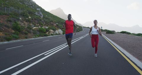 Diverse Fit Couple Running Outdoors on Mountain Road