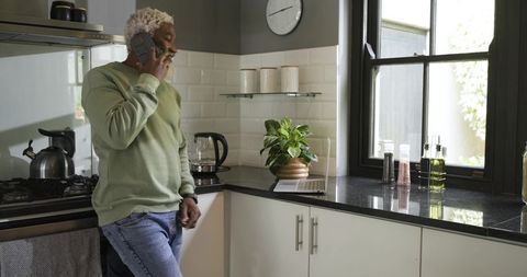 Senior Man Relaxing in Modern Kitchen Talking on Phone