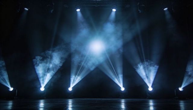 Blue spotlight beams piercing haze on stage for concert, theater, event promotion