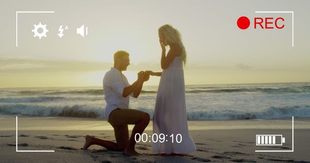 Caucasian couple enjoys a beach proposal at sunset. He's making a romantic gesture, offering a ring to his partner in a memorable moment.