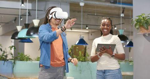 African American coworkers testing VR headset in modern open office collaboration