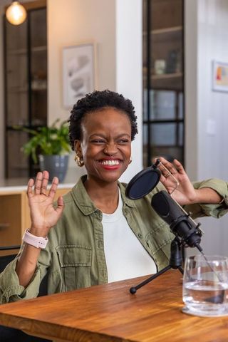 African american woman smiling recording podcast in cozy modern home studio