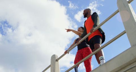 Couple interacting with each other near railing on a sunny day. Low angle view of couple standing near railing 4k