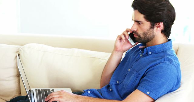 Young Man Working Remotely on Laptop and Talking on Smartphone at Home - Download Free Stock Images Pikwizard.com