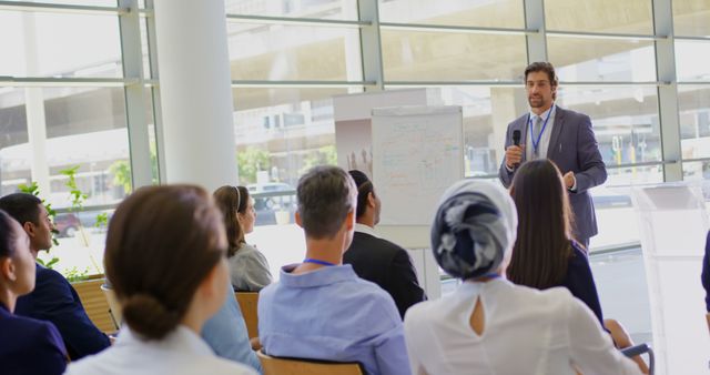 Front view of a Caucasian male speaker standing near a clipboard and speaking to the public in the business seminar 4k