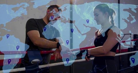 Boxing coach pointing at female boxer in ring with global network overlay