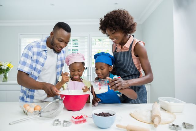 Family enjoying time together while preparing food in a modern kitchen. Parents and children are engaged in baking, mixing ingredients, and smiling, showcasing teamwork and bonding. Ideal for use in advertisements, family-oriented content, cooking blogs, and lifestyle articles.