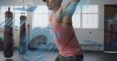 Male athlete raising arms overhead training with futuristic hud overlay in boxing gym
