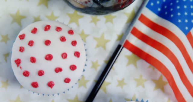 Festive cupcake decorated with red dots and accompanied by an American flag. Suitable for representing Independence Day celebrations, patriotic events, or American-themed parties. Can be used for social media posts, holiday invitations, event promotions, or festive food blogs to add a sense of patriotism and celebration.