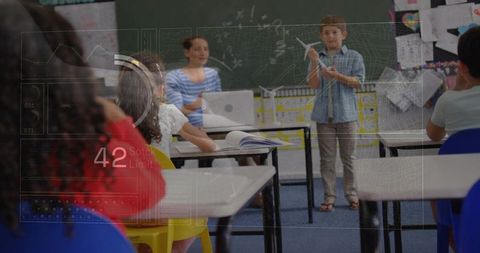 Elementary student presenting model airplane in classroom with futuristic HUD overlay