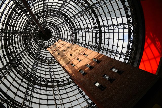 This image captures the striking contrast between a historic brick tower and a modern glass dome. The architecture highlights the integration of old and new, making it an excellent visual for articles or presentations on urban development, architectural design, or historical preservation. Ideal for use in educational resources, city guides, architectural portfolios, and marketing materials showcasing modern urban landscapes.