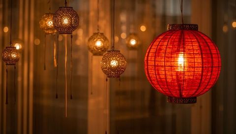 Glowing red paper lantern hanging with ornate metal lamps casting warm amber light