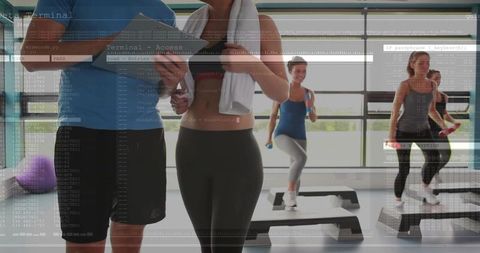 Fitness instructor checking client progress with clipboard during step class with digital overlay