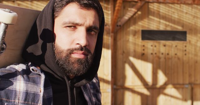 Bearded Young Man Holding Skateboard in Sunny Outdoor Setting - Download Free Stock Images Pikwizard.com