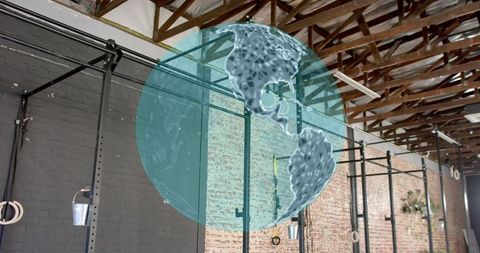 Floating holographic globe overlapping industrial gym interior with pull-up rig and trx