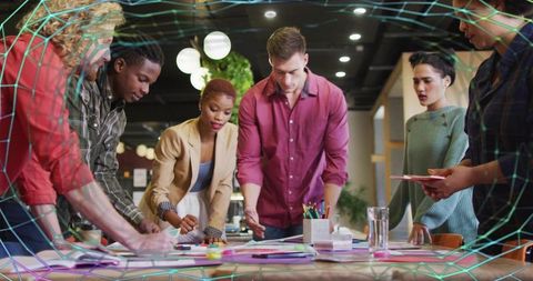 Creative team brainstorming around studio table with holographic grid overlay for products