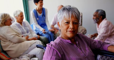 Confident senior woman in nursing home with friends